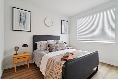 A bedroom with a bed, nightstand, and window.