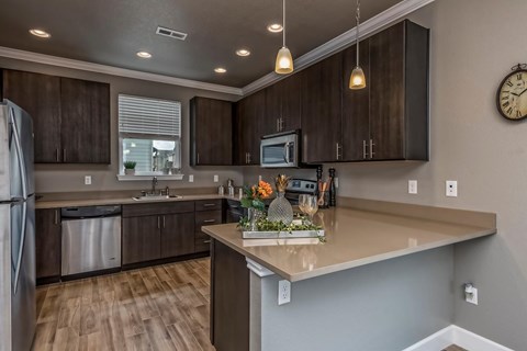 A kitchen with brown cabinets and a wooden floor.