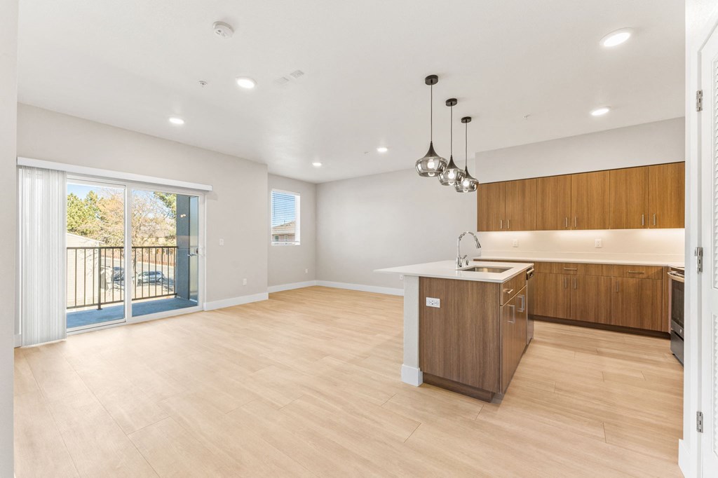 an open kitchen and living room with a sliding glass door to a balcony