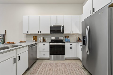 A modern kitchen with white cabinets and stainless steel appliances.
