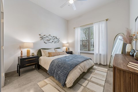A bedroom with a bed, nightstand, and a ceiling fan.