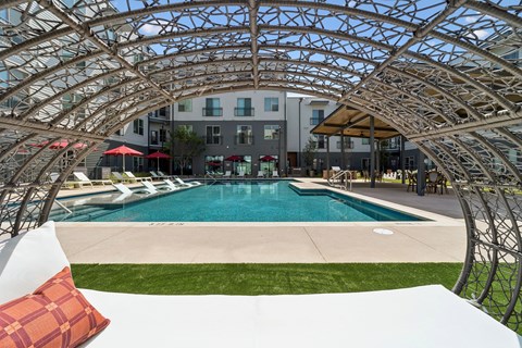A pool surrounded by a white wall and a metal trellis.