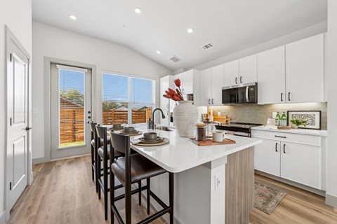 A kitchen with a table and chairs in front of a window.