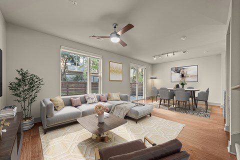 A living room with a grey couch, a coffee table, and a dining table with chairs.