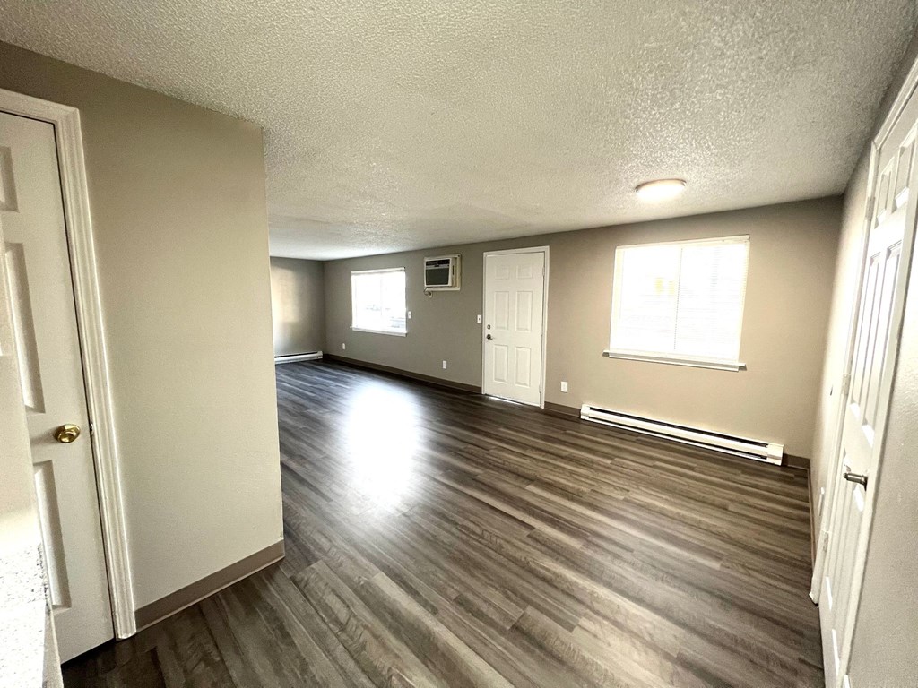 an empty living room with hard wood floors and a window