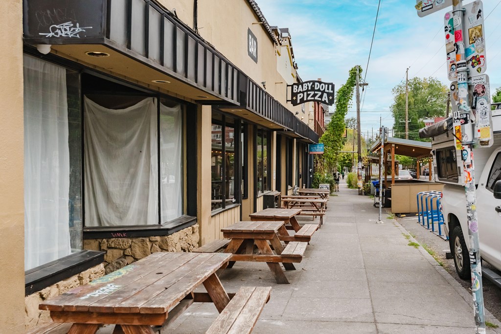 A Baby Doll Pizza restaurant has wooden picnic tables outside.