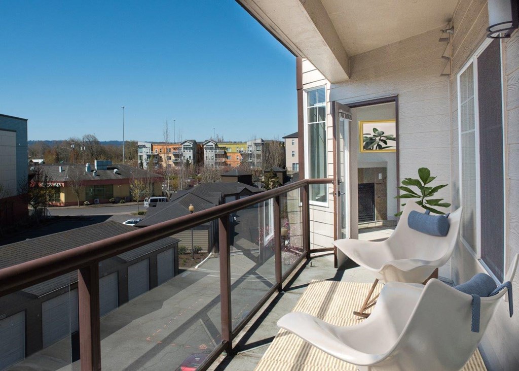 a balcony with two white chairs and a fireplace