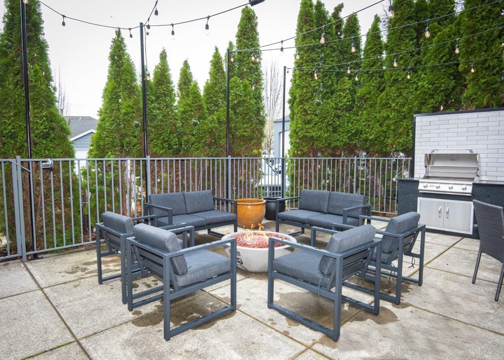 a patio with a fire pit and chairs