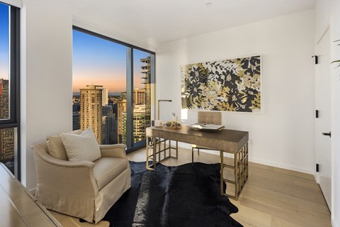 A living room with a chair, a table, and a painting on the wall.