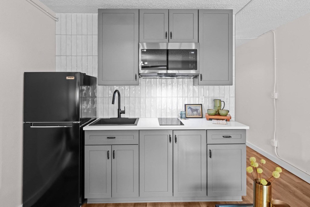 a kitchen with white cabinets and a black refrigerator