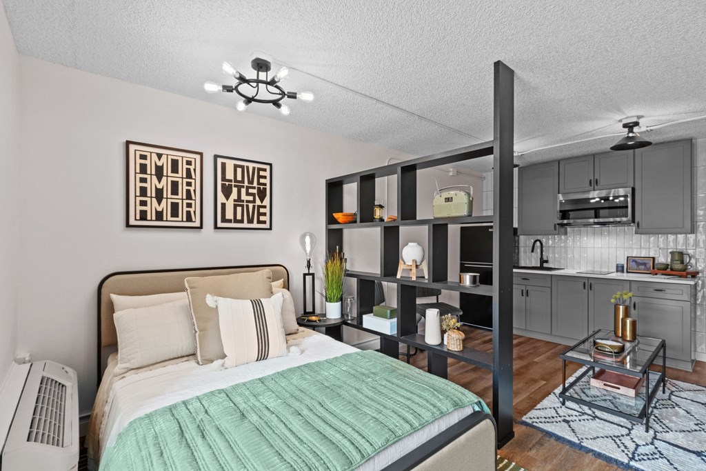 a bedroom with a bed and a kitchen with gray cabinets