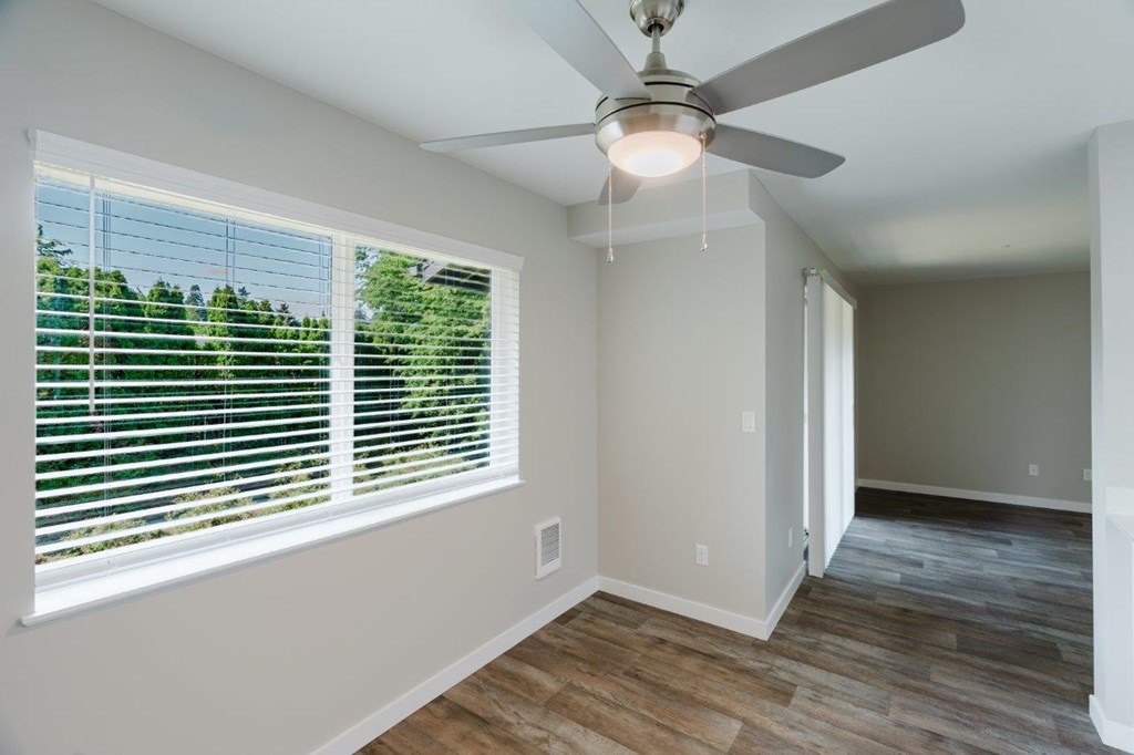 A room with a ceiling fan and a window with blinds.