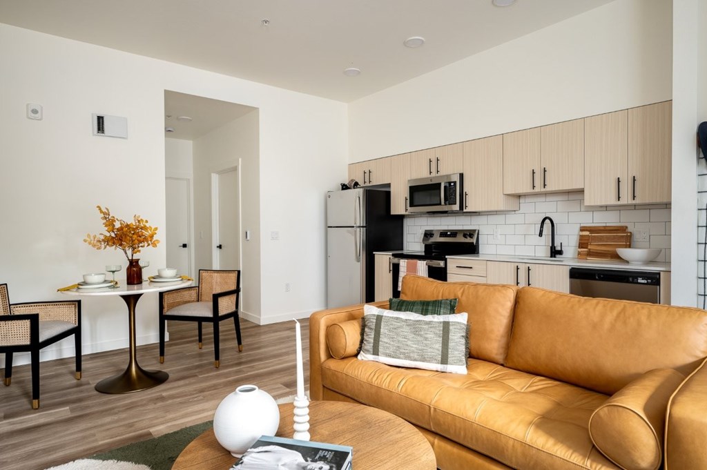 The Wes Gresham Oregon Apartments A modern kitchen with a tan couch and a round table.
