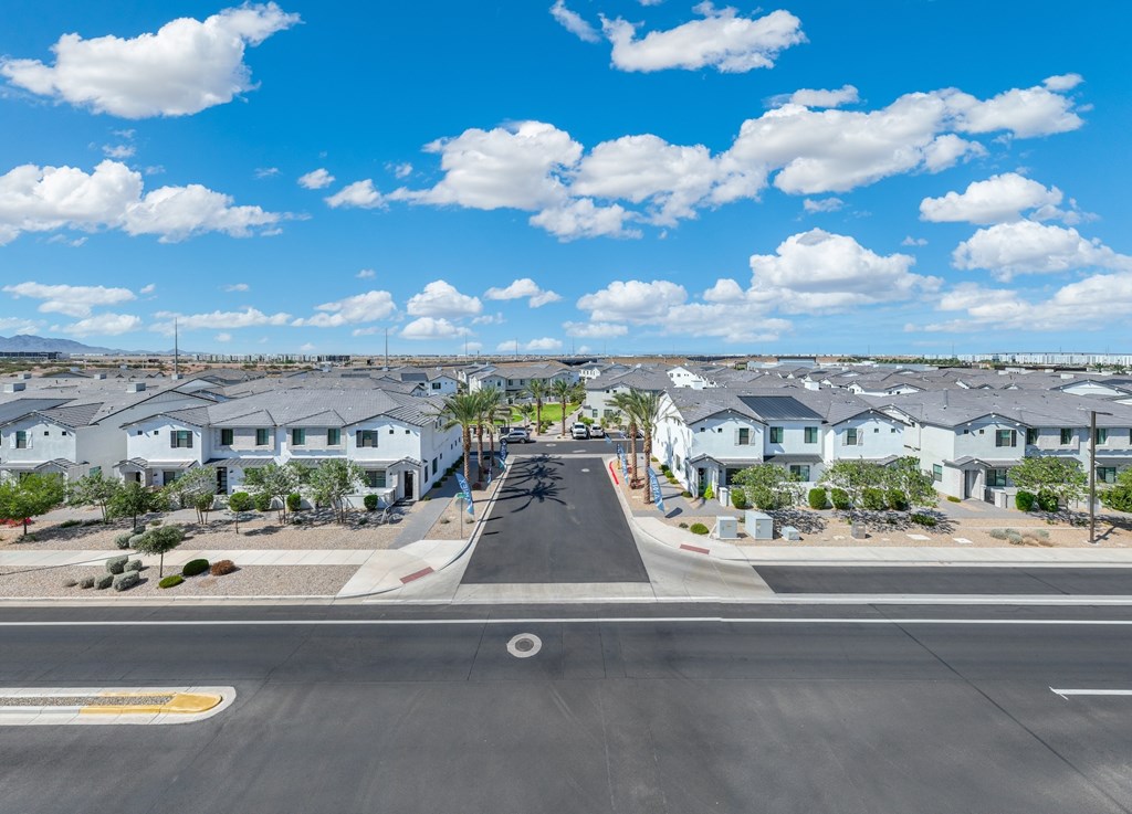 A street view of a residential area with houses on both sides and a clear blue sky above.
