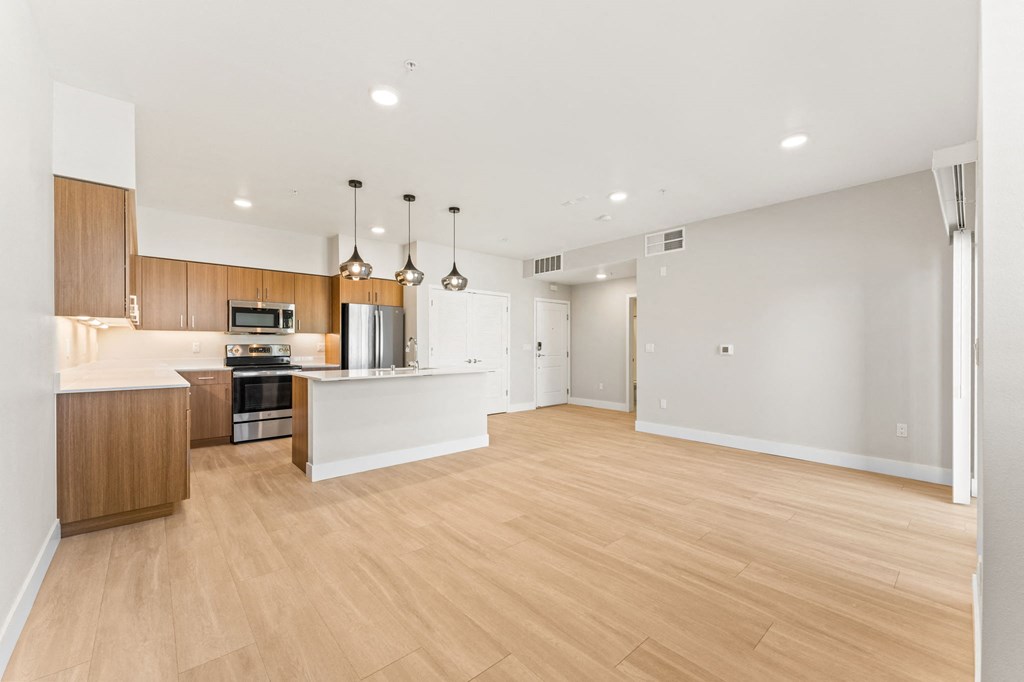 an open kitchen and living room with wood floors and white walls