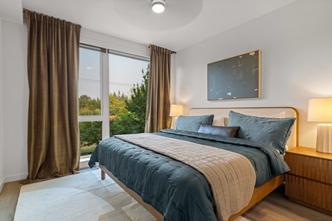 A bedroom with a large bed and a window overlooking a green landscape.