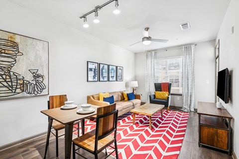 A living room with a red and white rug and a painting of a cocktail glass on the wall.