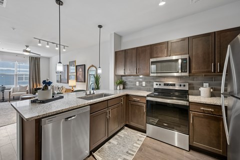 A modern kitchen with dark brown cabinets and stainless steel appliances.