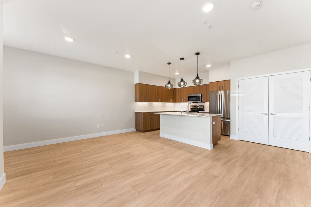 an empty living room and kitchen with wood flooring