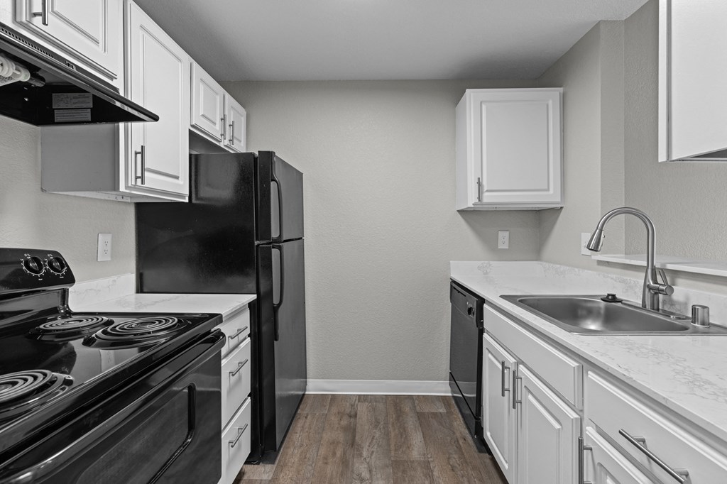 an empty kitchen with white cabinets and black appliances