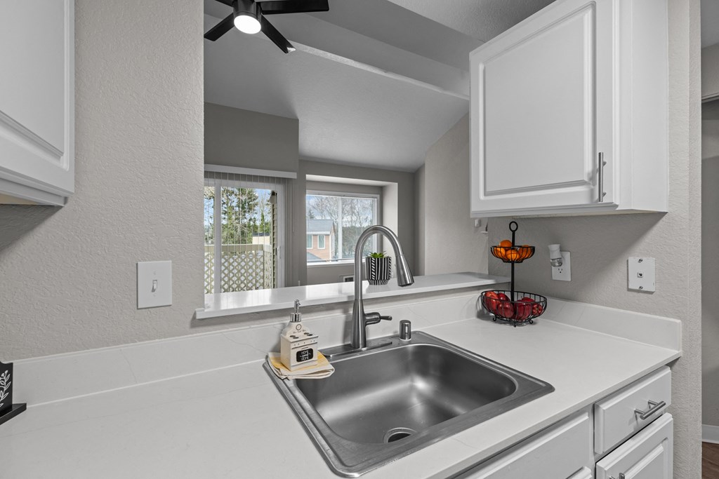 the kitchen of our studio apartment has a stainless steel sink and white cabinets