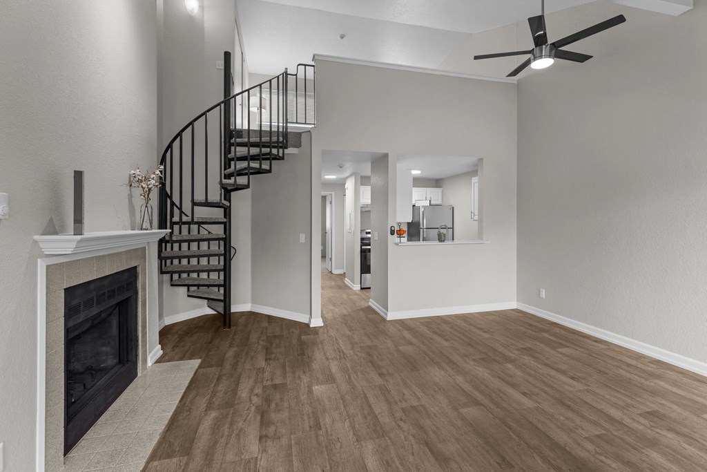 an empty living room with a fireplace and a spiral staircase