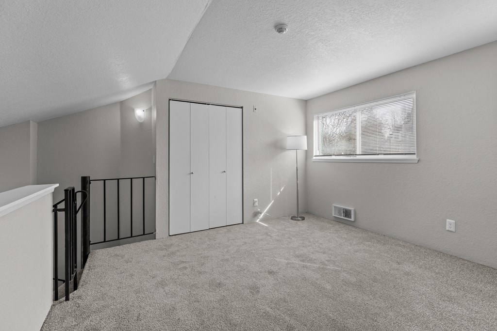 the living room of an apartment with a staircase and a window