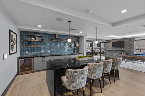 A modern kitchen with a black countertop and a dining table with chairs.