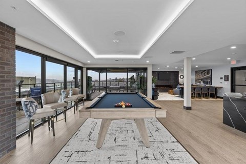 A billiard table is in the middle of a room with a brick wall and a pool table.