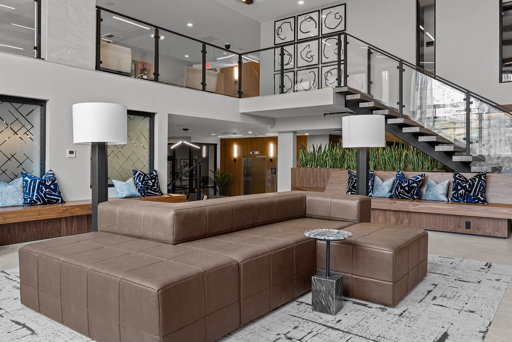 a living room with a brown couch and a staircase