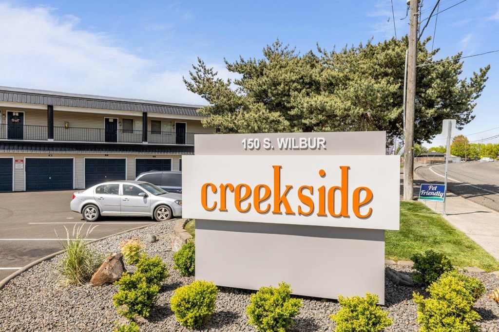 A sign for Creekside apartment complex stands in front of a building.
