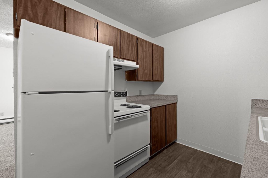 A white refrigerator is in a kitchen with brown cabinets.