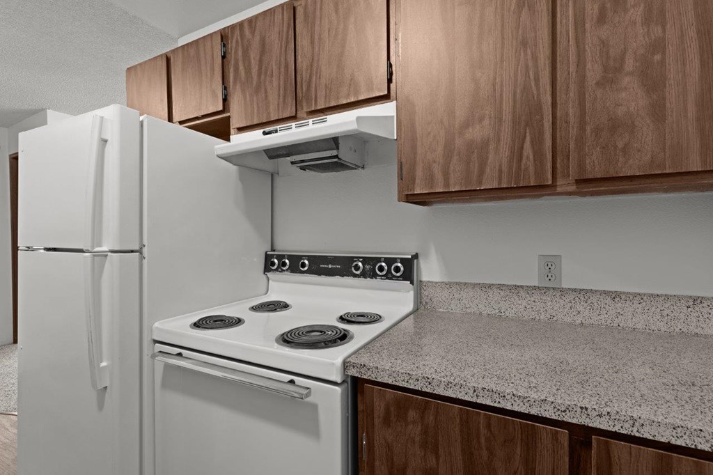 A white stove and refrigerator in a kitchen with wooden cabinets.