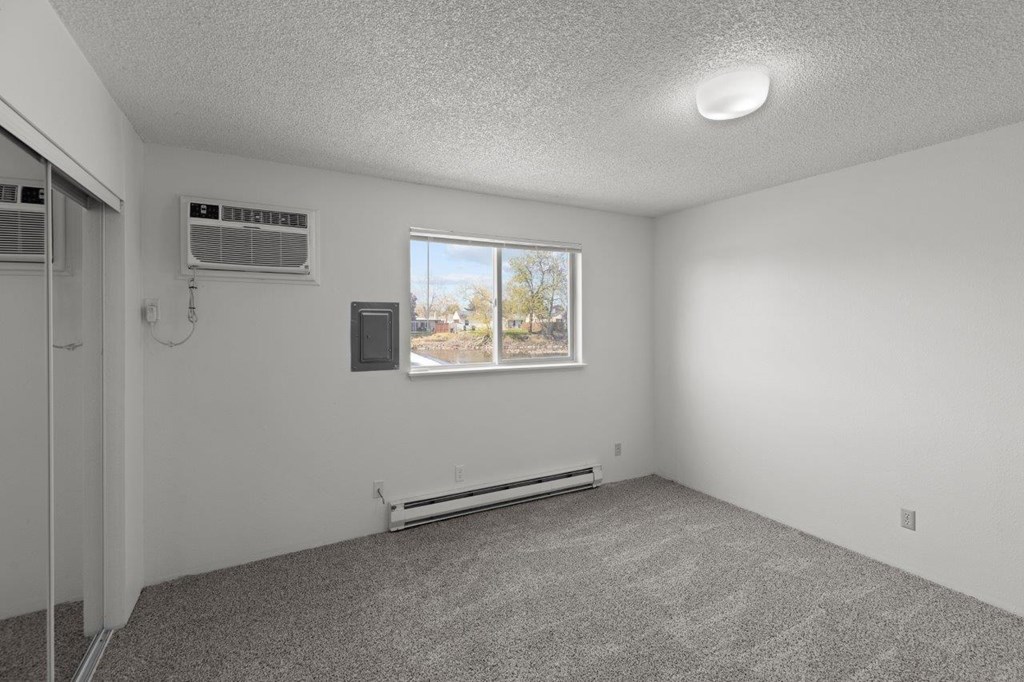 A room with a window and two air conditioning units.