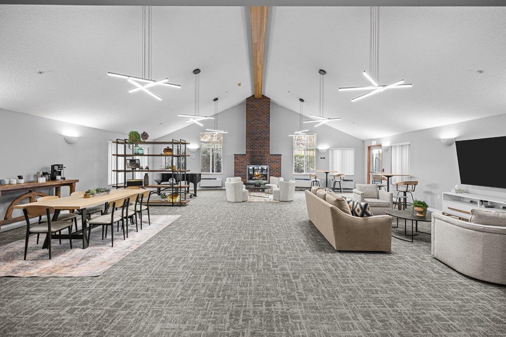 A modern living room with a grey carpet and a variety of furniture.