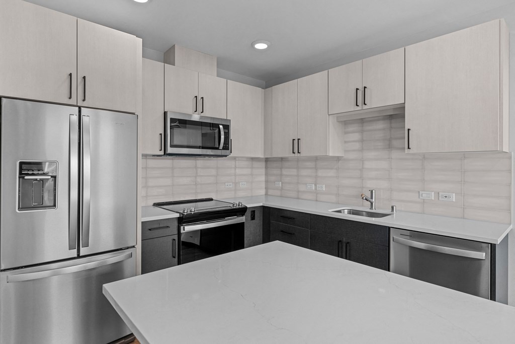 an all white kitchen with stainless steel appliances and white counter tops