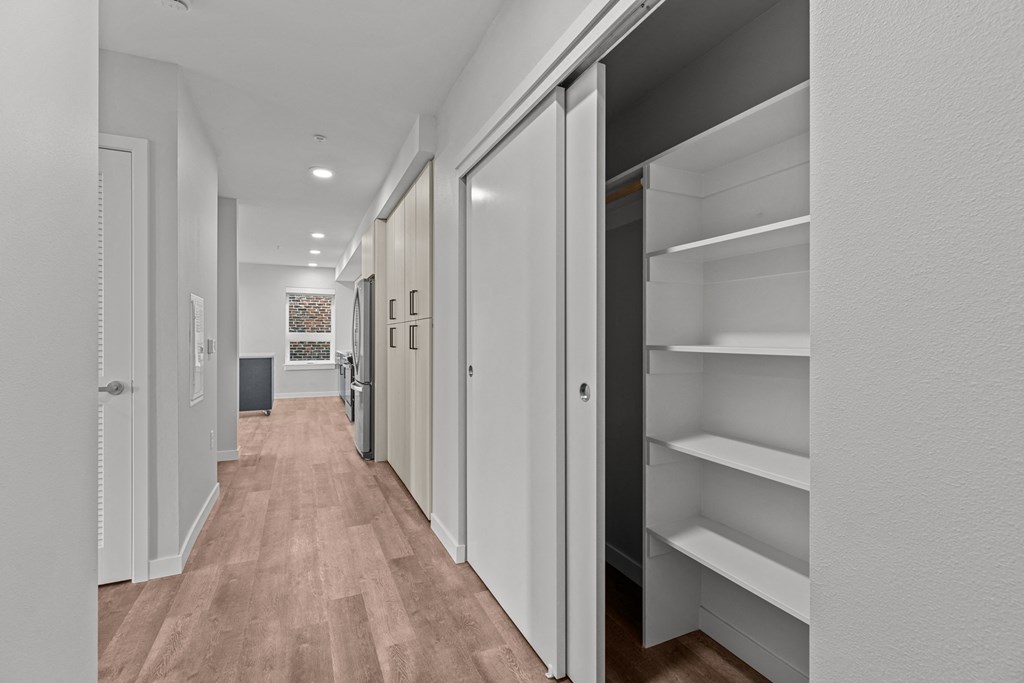 a long hallway with white closets and wood floors