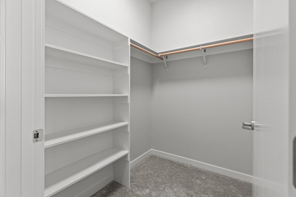 a walk in closet in a home with empty shelves