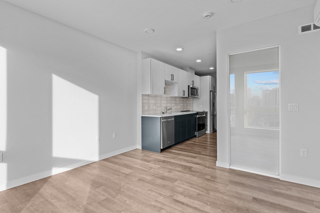the living room and kitchen in a new home with white walls and wood flooring