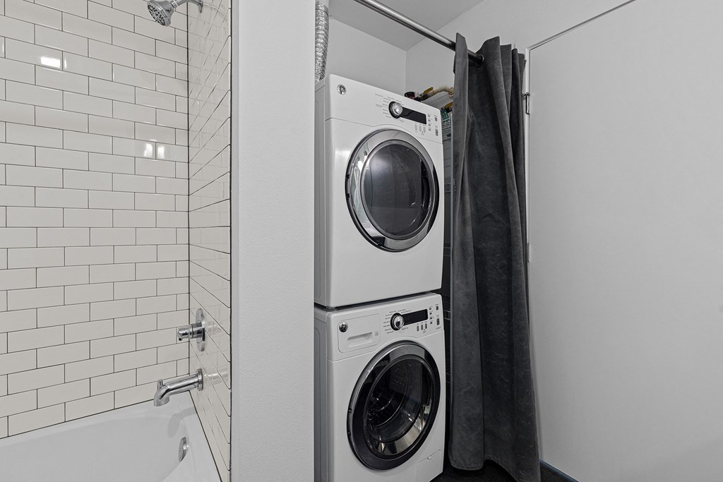 a small laundry room with a washing machine and a shower