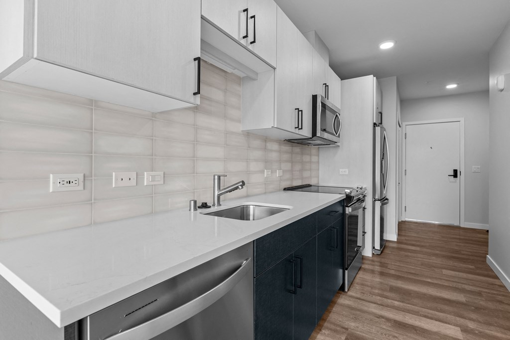 a kitchen with white countertops and a stainless steel sink