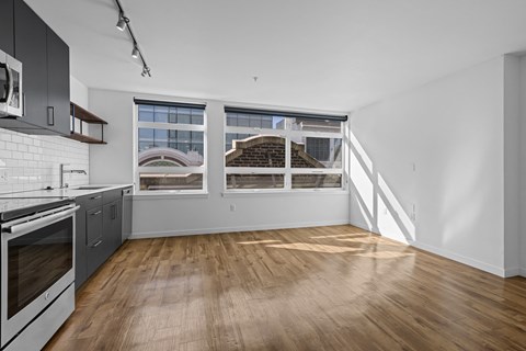 an empty kitchen with white walls and wood floors and a window
