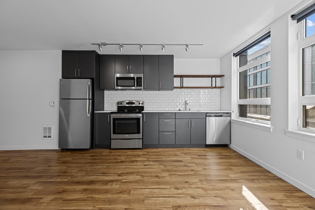 a kitchen with black cabinets and a stainless steel refrigerator