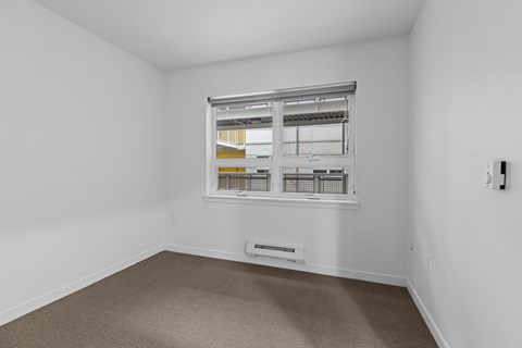 room with a window and white walls and carpeting