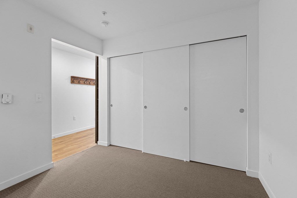 a bedroom with white walls and white closet doors
