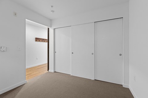 a bedroom with white walls and white closet doors