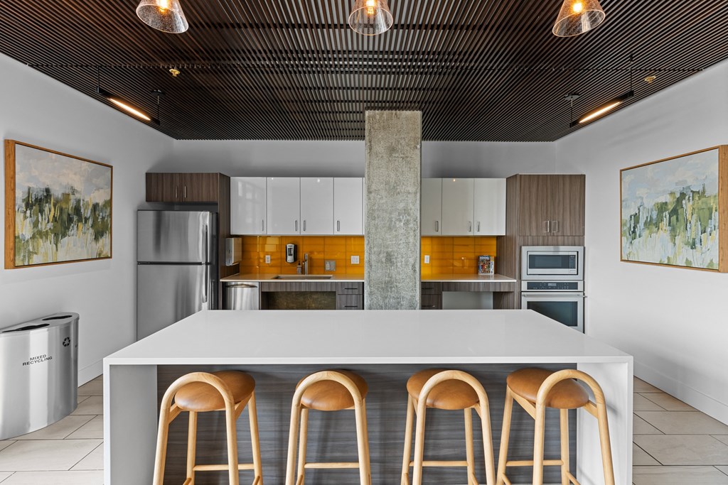 a kitchen with a white counter top and four stools