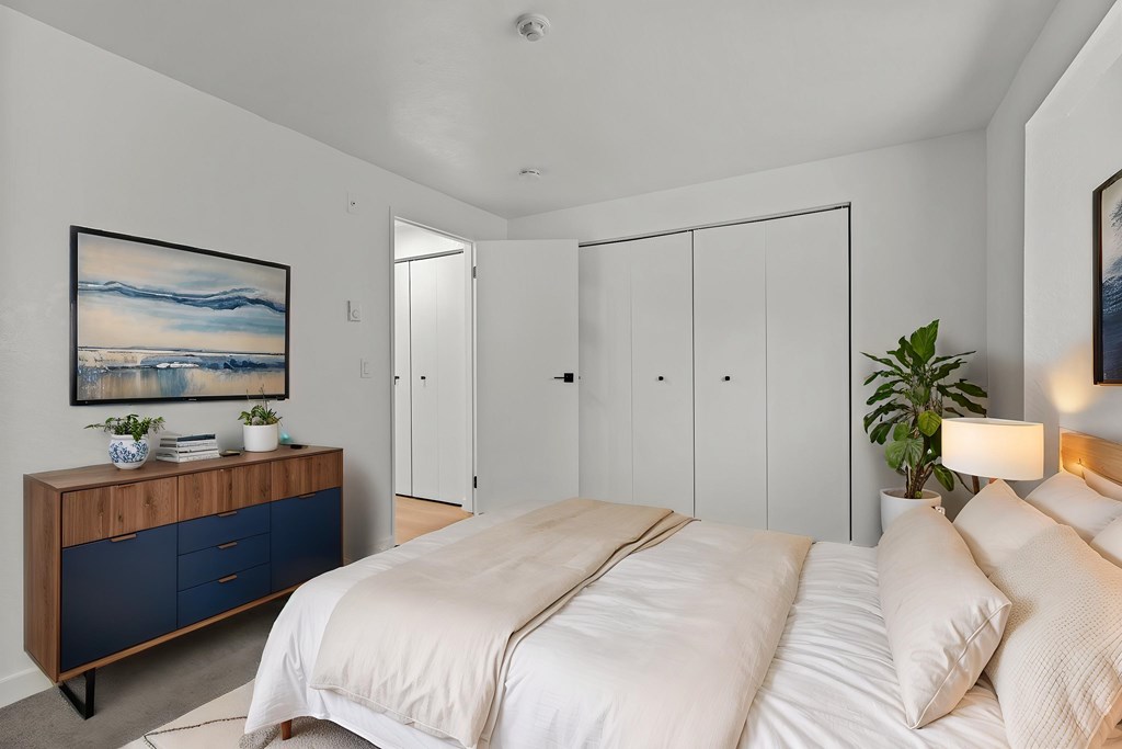 A bedroom with a large bed and a wooden cabinet with blue drawers.