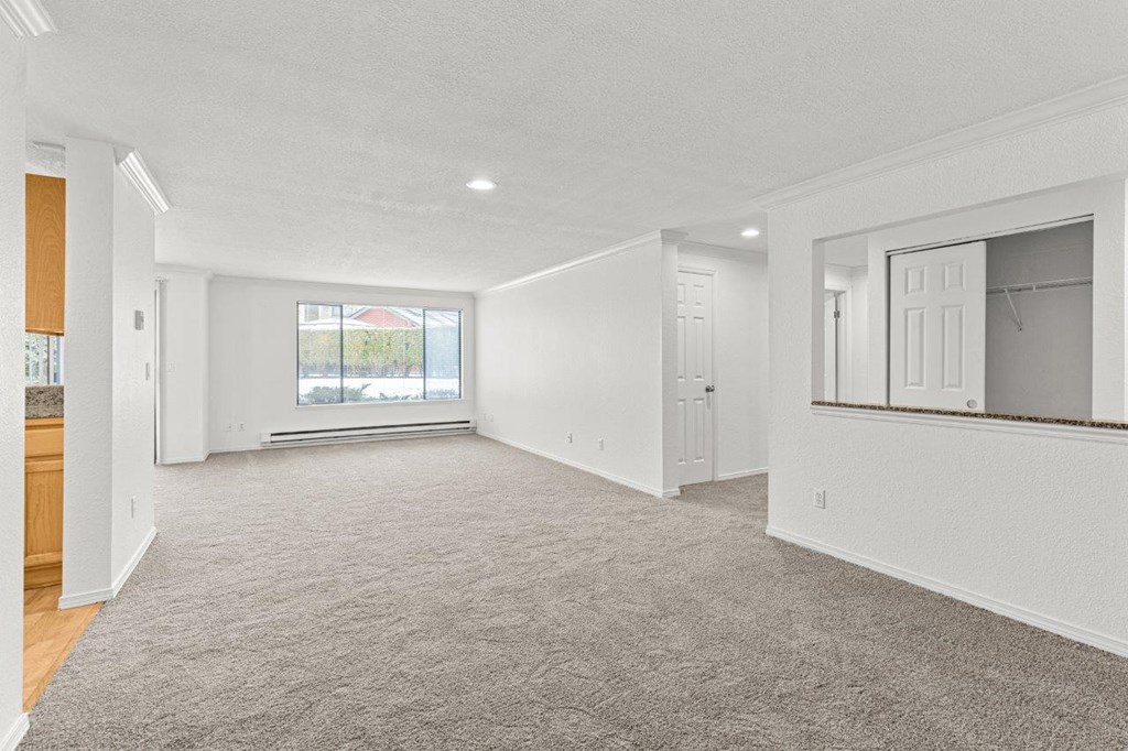 A spacious, empty room with a carpeted floor and white walls.