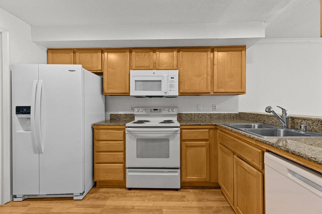 A white refrigerator is in a kitchen with wooden cabinets.